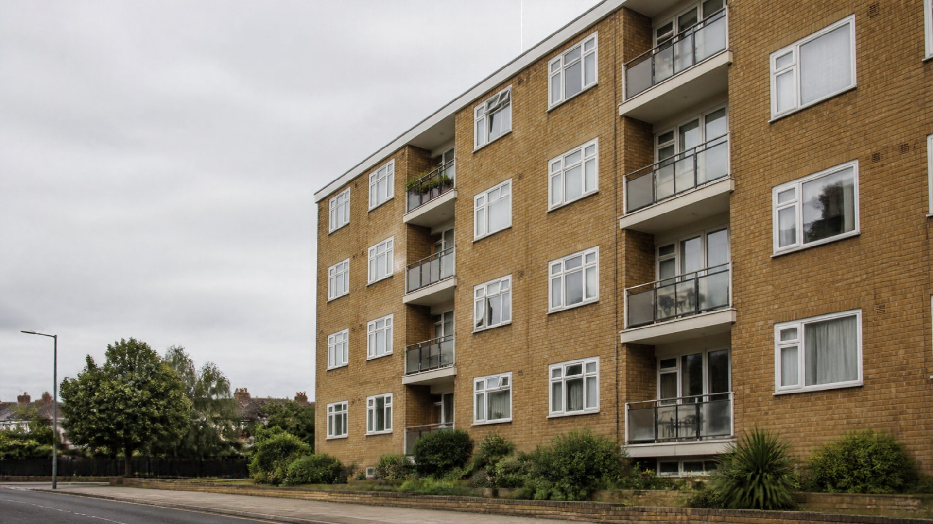 The exterior of a plain modern brick apartment block on an ordinary street